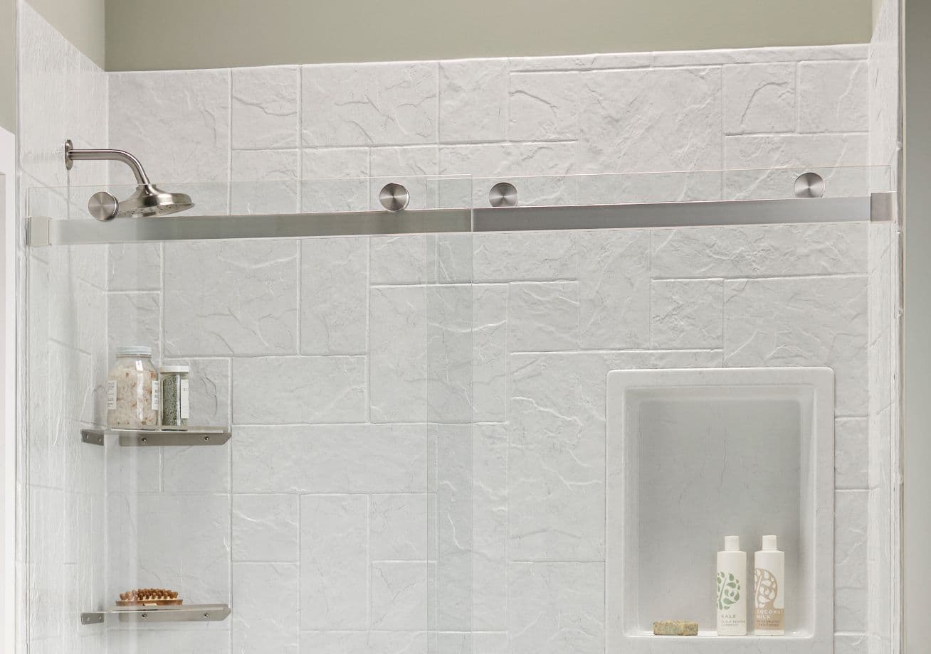 Modern shower enclosure with white marble-look tiles, rain showerhead, brushed nickel fixtures, recessed niche with toiletries, and stainless steel shelving